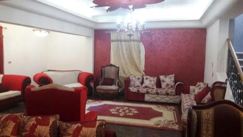 ein Wohnzimmer mit roten Möbeln und einem Kronleuchter in der Unterkunft Octobar City Villa in Kairo
