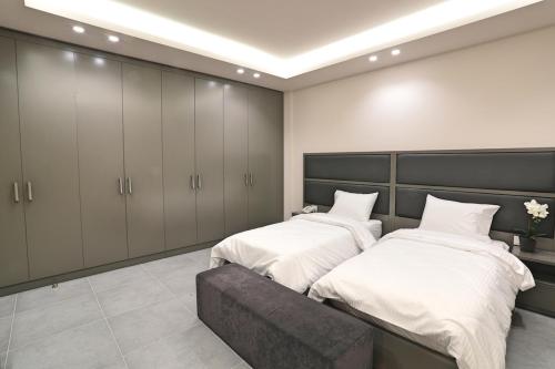 a bedroom with two beds and a bench in it at The Residence 649 in An Naqqāsh