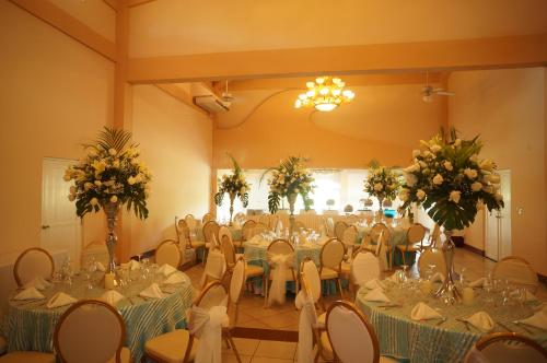 a banquet hall with tables and chairs and flowers at Las Olas Beach Resort in La Barqueta