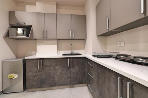 a kitchen with gray and white cabinets and a sink at The Residence 649 in An Naqqāsh