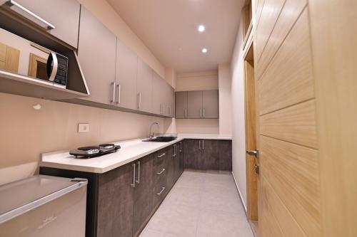 a kitchen with white counters and wooden cabinets at The Residence 649 in An Naqqāsh