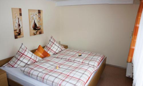 Bett mit karierten Kissen in einem Schlafzimmer in der Unterkunft Ferienwohnung Haus Franziska in Neuschönau