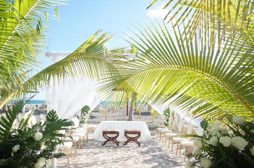 a table and chairs on the beach under a palm tree at Las Olas Beach Resort in La Barqueta
