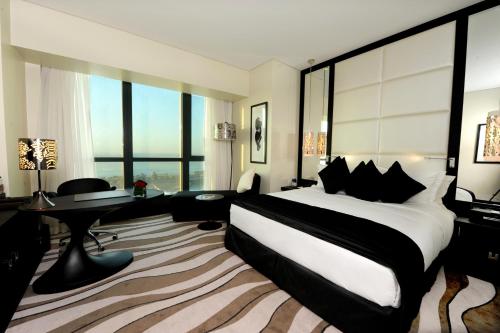 a hotel room with a large bed and a desk at Sofitel Abu Dhabi Corniche in Abu Dhabi