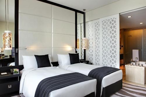 a bedroom with a large white bed and a bathroom at Sofitel Abu Dhabi Corniche in Abu Dhabi