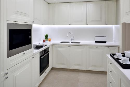 a white kitchen with white cabinets and a sink at Kempinski The Boulevard Dubai in Dubai