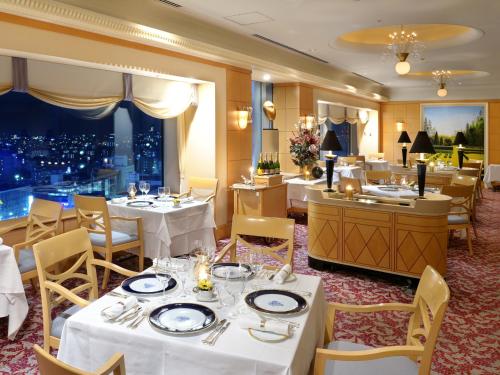 a restaurant with white tables and chairs and a city at Hotel Granvia Okayama in Okayama