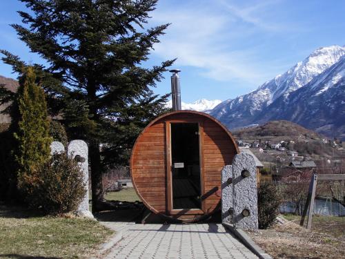 a small building with a door in a field with mountains at La Roche Hotel Appartments in Aosta