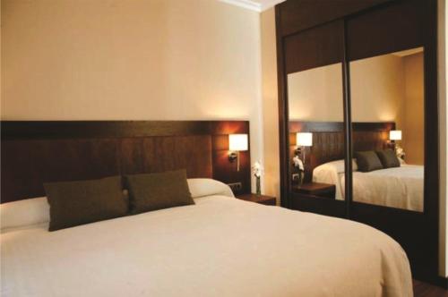 a hotel room with two beds and two lamps at Hotel Villa de Aranda in Aranda de Duero
