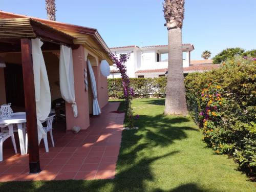 un patio con una mesa y una palmera en Villino Asfodeli, en San Teodoro