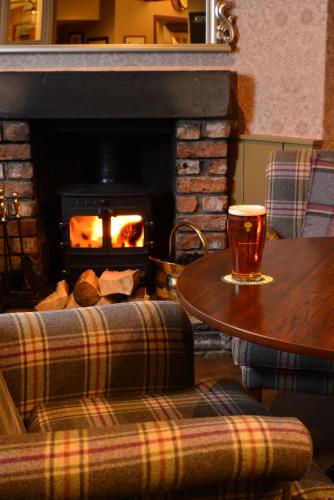 a living room with a fireplace and a table and a fire place at The Devonshire Grassington in Grassington
