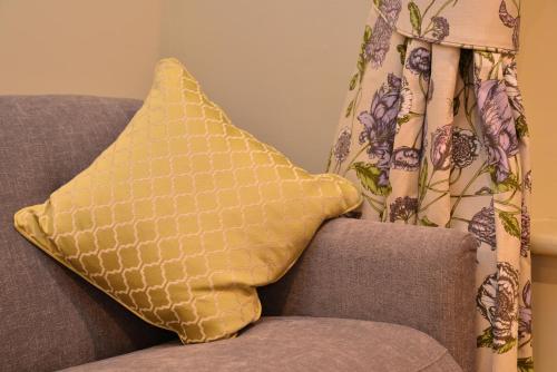 a yellow pillow sitting on a couch with a curtain at The Devonshire Grassington in Grassington