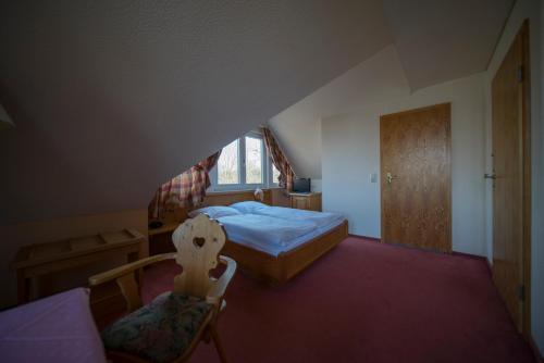 ein Schlafzimmer mit einem Bett und einem Stuhl im Dachgeschoss in der Unterkunft Gasthaus Zum Frohsinn in Bosau