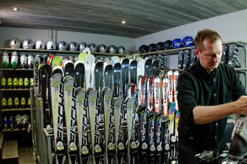 a man standing in front of a rack of skis at Hotel Ambassador Zermatt in Zermatt