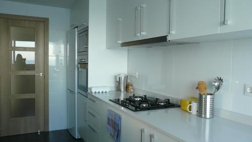 a white kitchen with a stove and white cabinets at Apartamento primera línea de playa in Benicàssim