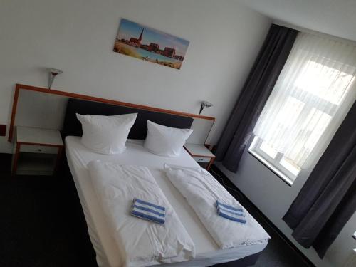 a bedroom with a bed with white sheets and pillows at Appartement-Hotel Rostock in Rostock