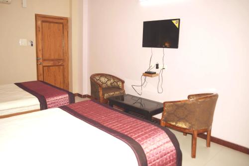 a hotel room with two beds and chairs and a tv at Hotel Abhilasha in Giriak