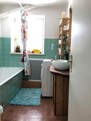 ein Bad mit einem Waschbecken, einer Badewanne und einem Fenster in der Unterkunft Atelierwohnung Jirana in Saalfelden am Steinernen Meer