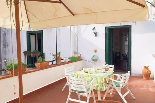 a table with chairs and an umbrella on a patio at Casa Pollio in Meta