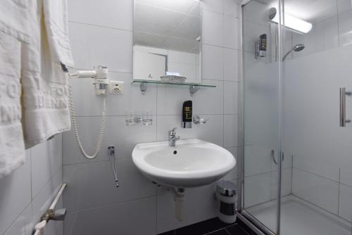 ein weißes Badezimmer mit Waschbecken und Dusche in der Unterkunft Hotel Dufour in Biel