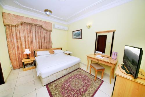 a bedroom with a bed and a television at Muscat International Hotel in Muscat