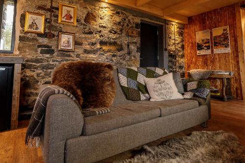 a couch in a living room with a stone wall at Lusa Bothy in Lusa