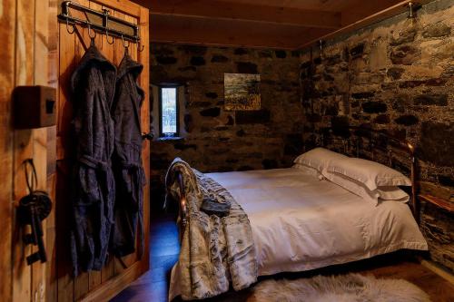 a bedroom with a bed in a stone wall at Lusa Bothy in Lusa