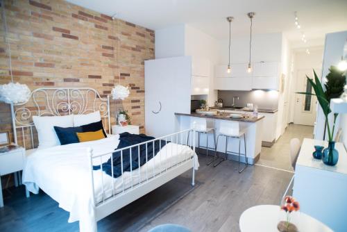 ブダペストにあるCharming Trees Apartmentの白いベッドとレンガの壁が備わるベッドルーム1室が備わります。