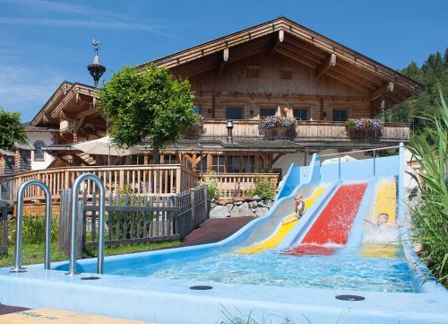 a pool with a slide in front of a house at Familienparadies Sporthotel Achensee - FAMILIES ONLY in Achenkirch