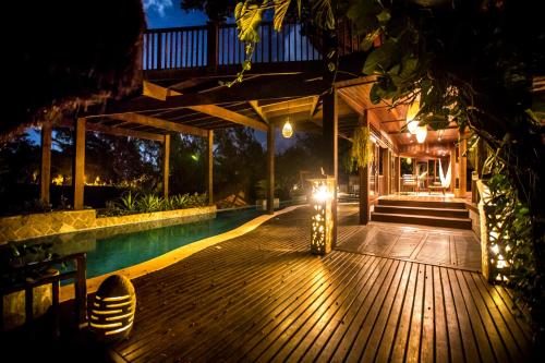 a wooden deck with a swimming pool at night at Sombra e Água Fresca Floresta in Pipa