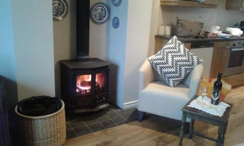 a living room with a fireplace and a chair and a stove at Coastguard Cottage in Newcastle