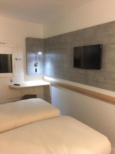 a hotel room with a bed and a flat screen tv at Ibis Budget Le Havre Les Docks in Le Havre