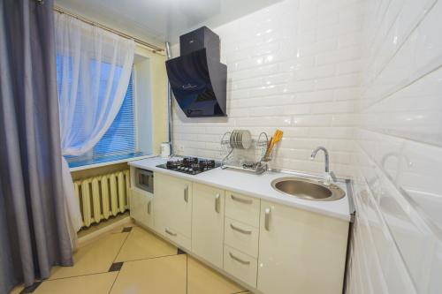 a small white kitchen with a sink and a window at Апартаменты в центре на проспекте Мира от ApartmentCity in Mogilev