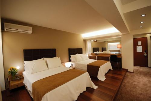 a hotel room with two beds and a bathroom at Capsis Hotel Thessaloniki in Thessaloniki