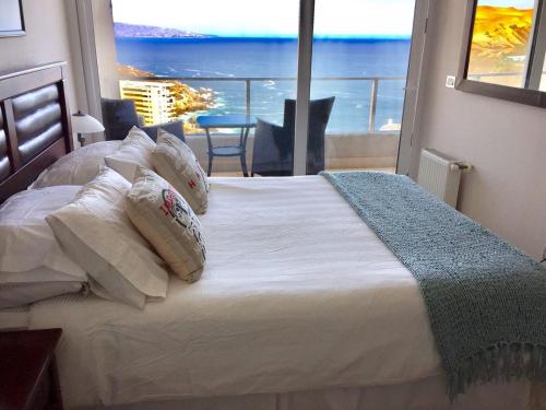 a bedroom with a bed with a view of the ocean at Departamento Costa de Montemar in Concón