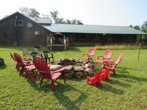 a group of red chairs sitting around a fire pit at Tug Hill Resort in Redfield