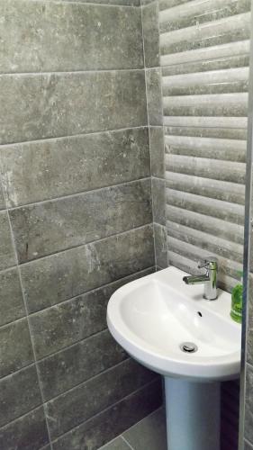 a bathroom with a white sink and a tile wall at Number 4 in Derry Londonderry