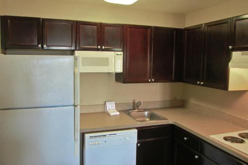 a kitchen with brown cabinets and a white refrigerator at Extended Stay America Suites - Memphis - Wolfchase Galleria in Memphis