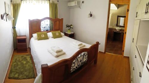 a bedroom with a large bed with white sheets and green pillows at La Perla Hotel in Santa Cruz