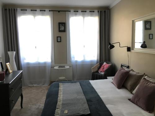 a bedroom with a large bed and two windows at Appartement Erik Satie in Honfleur