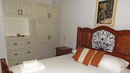 a bedroom with a bed with a dresser and a bike painting at La Perla Hotel in Santa Cruz