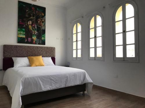 a bedroom with a bed with a yellow pillow and two windows at Larq'a Park Rooms in Lima