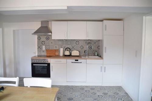 a kitchen with white cabinets and a table and chairs at Maison Cyriax in Harzgerode