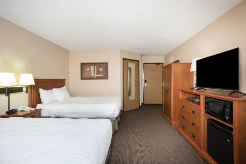 a hotel room with two beds and a flat screen tv at AmericInn by Wyndham Sioux City in Sioux City