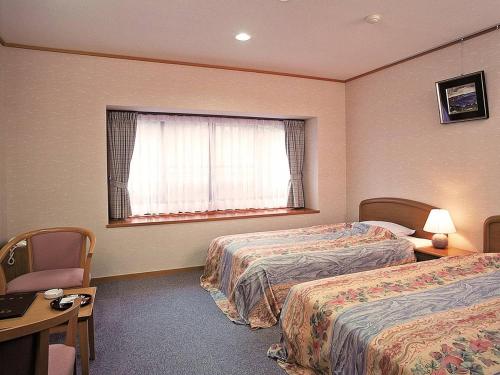 a hotel room with two beds and a window at Itoen Hotel Shima in Nakanojo