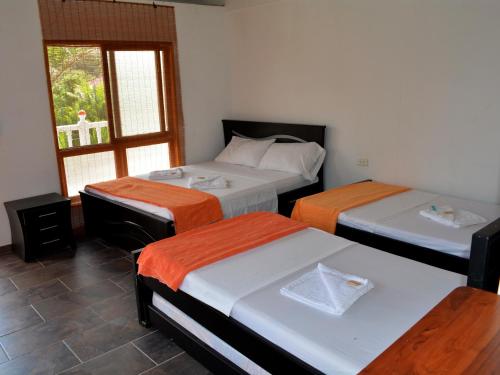 three beds in a room with a window at Hotel Campestre La Toscana in Villavicencio