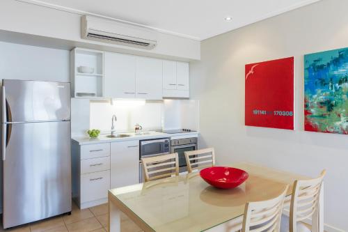 a kitchen with a dining table and a refrigerator at Nesuto Geraldton in Geraldton