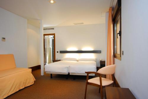 um quarto de hotel com uma cama e uma cadeira em Hotel Domus Plaza Zocodover em Toledo