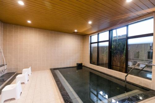 a swimming pool with white chairs and a large window at Hotel Binario Saga Arashiyama in Kyoto