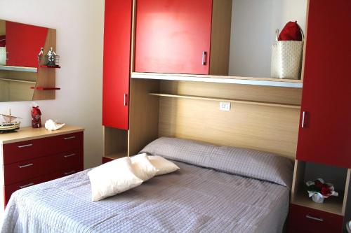 リド・デッレ・ナツィオーニにあるAirone Bianco Residence Villageの赤いキャビネットとベッド付きのベッドルーム1室